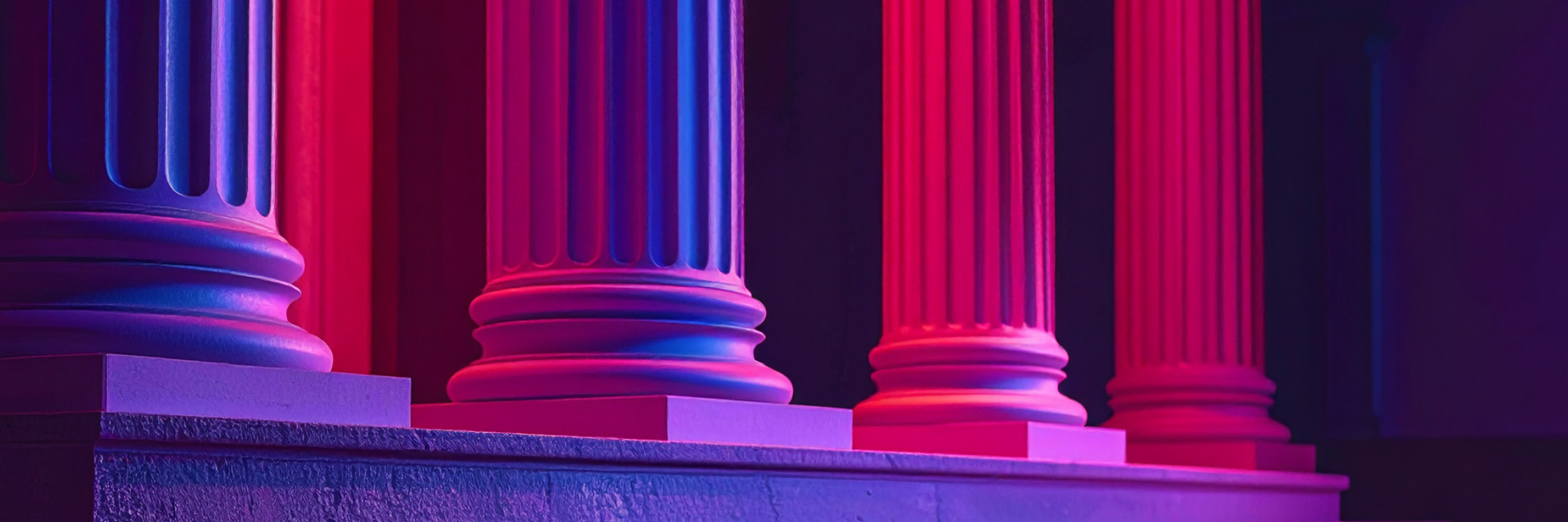 Grassi_Website_Image_TE_RPPTL-Legislative-Update_2025-08_FA Close-up of classical architectural columns with dramatic pink and blue lighting.